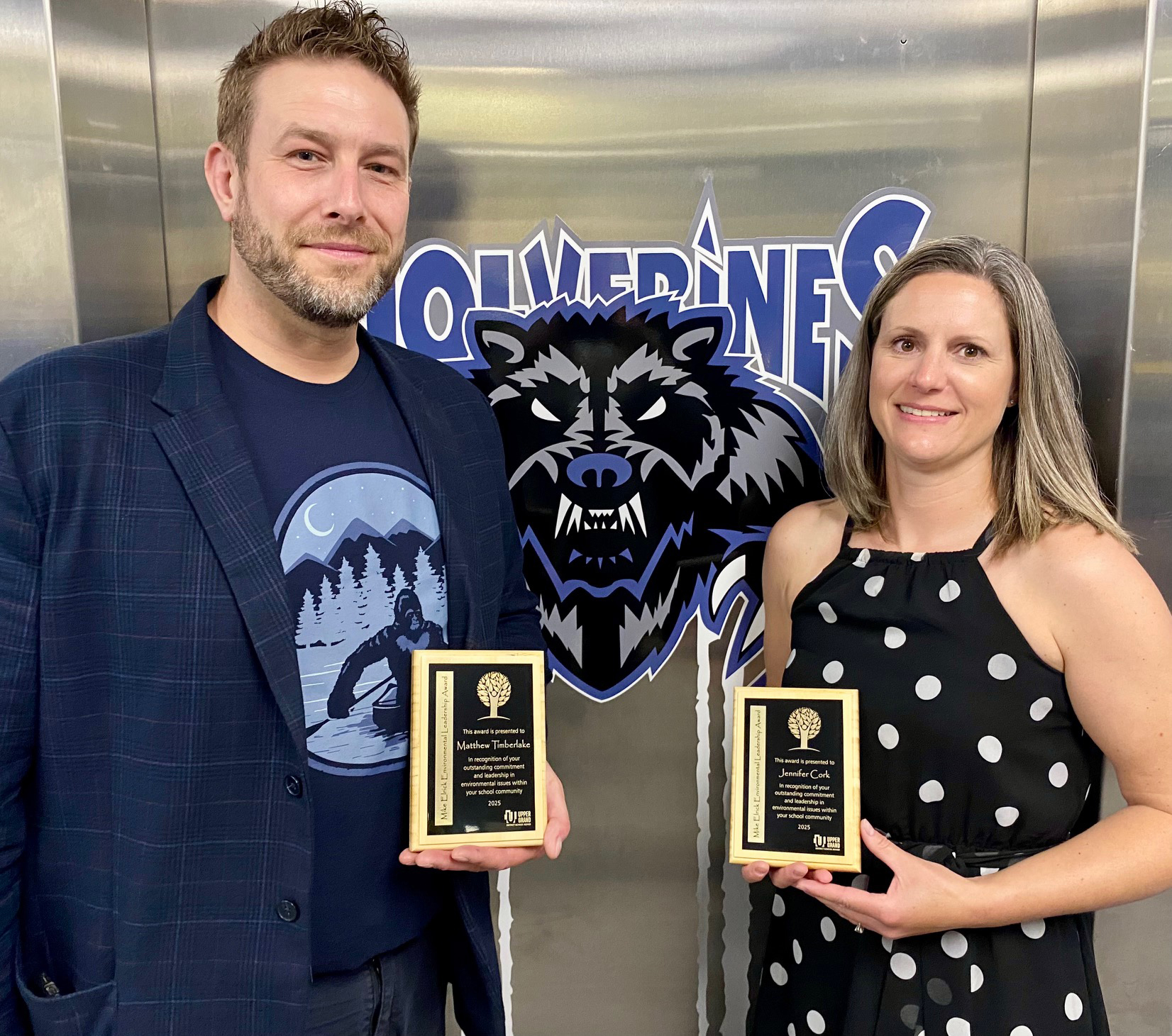 Two educators are pictured holding small plaques.