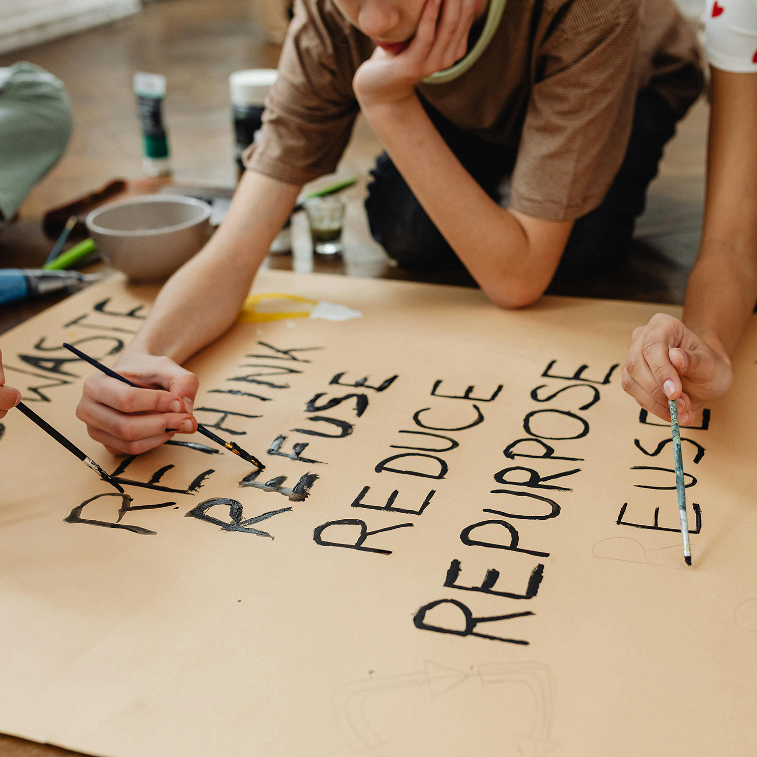 students work on a poster with the words reduce, reuse