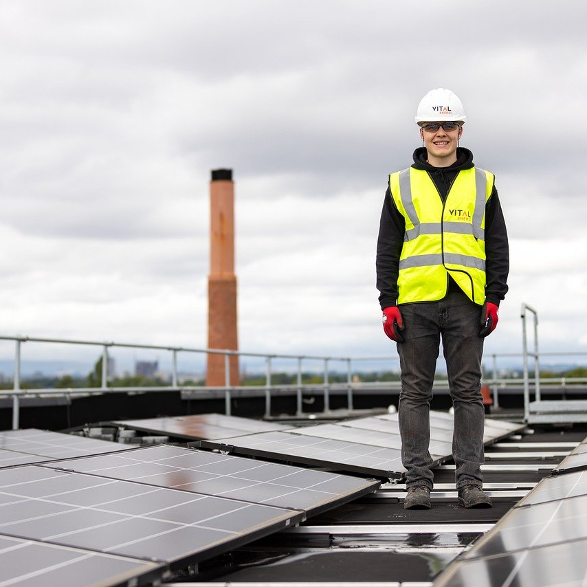 student standing on roof next to solar panels