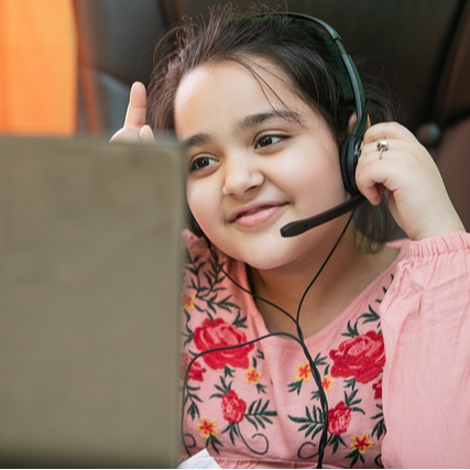 A student sits at a laptop with headphones on