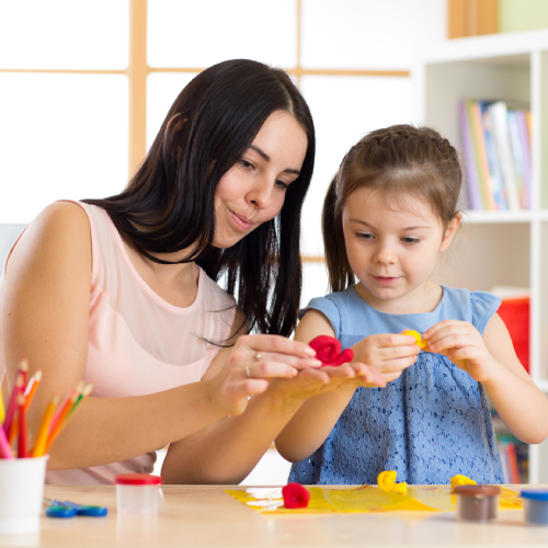 An educator and a young student play with crafts