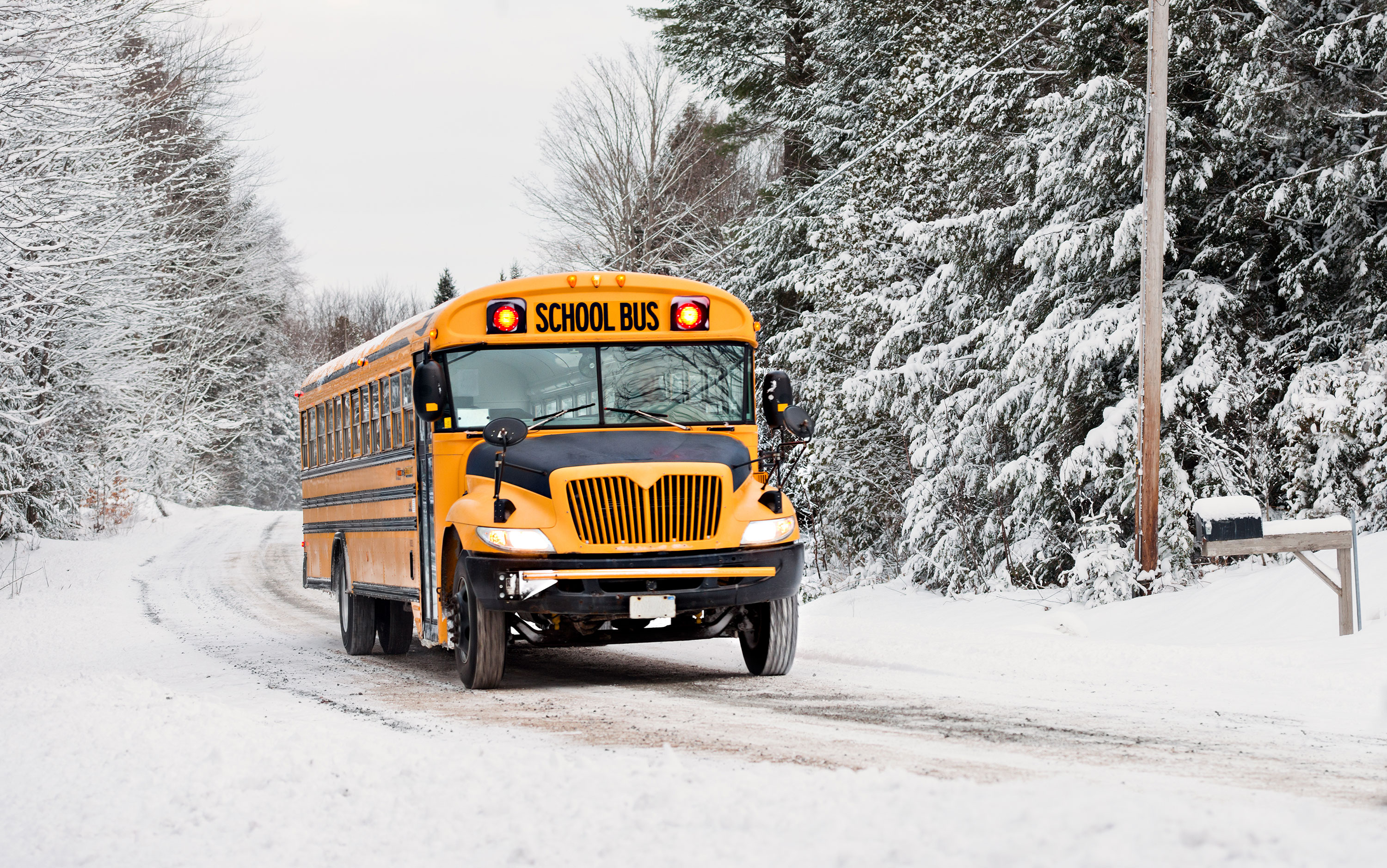 A yellow school bus driving on a snowy road.