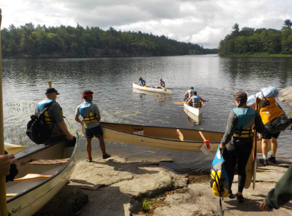 Students putting canoes in the water.