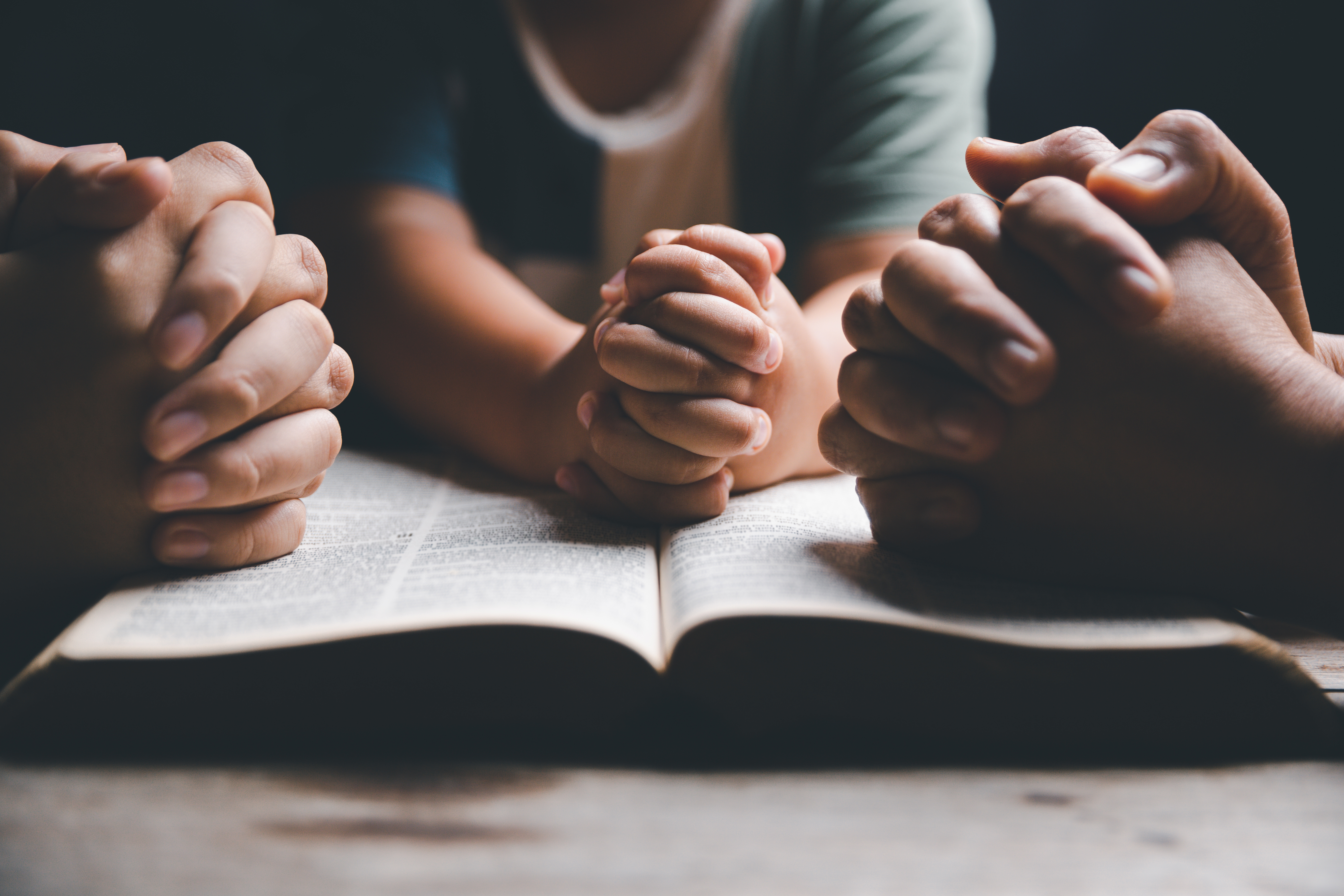 hands praying on bible