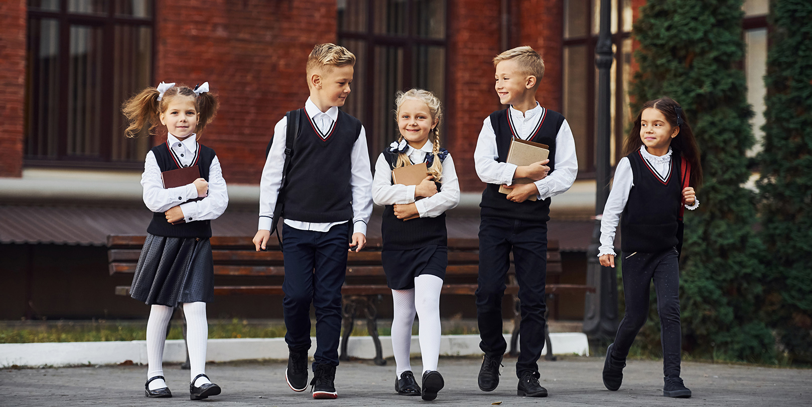 Children in uniforms walking in front of school