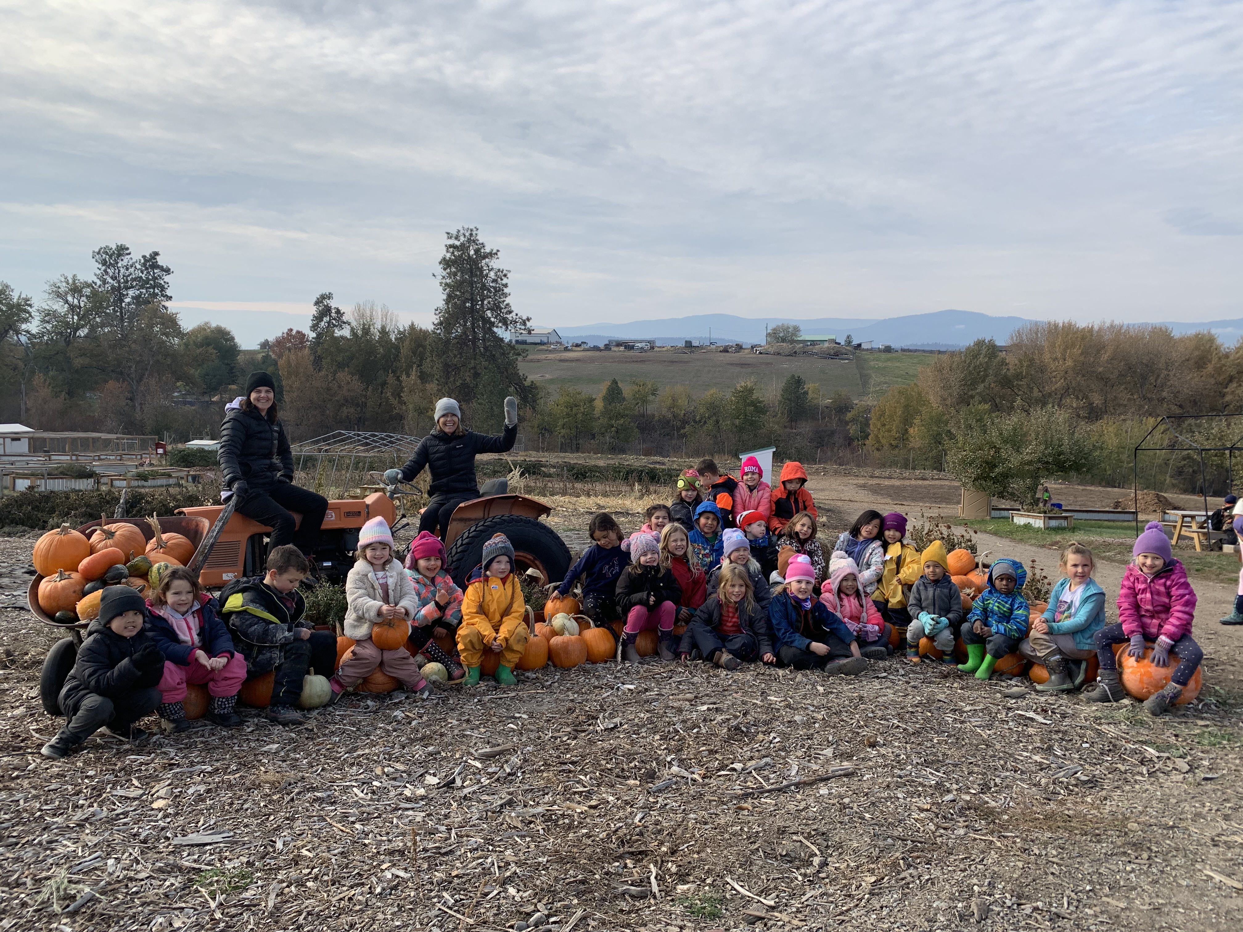 teachers and their students sitting outside in a tractor field