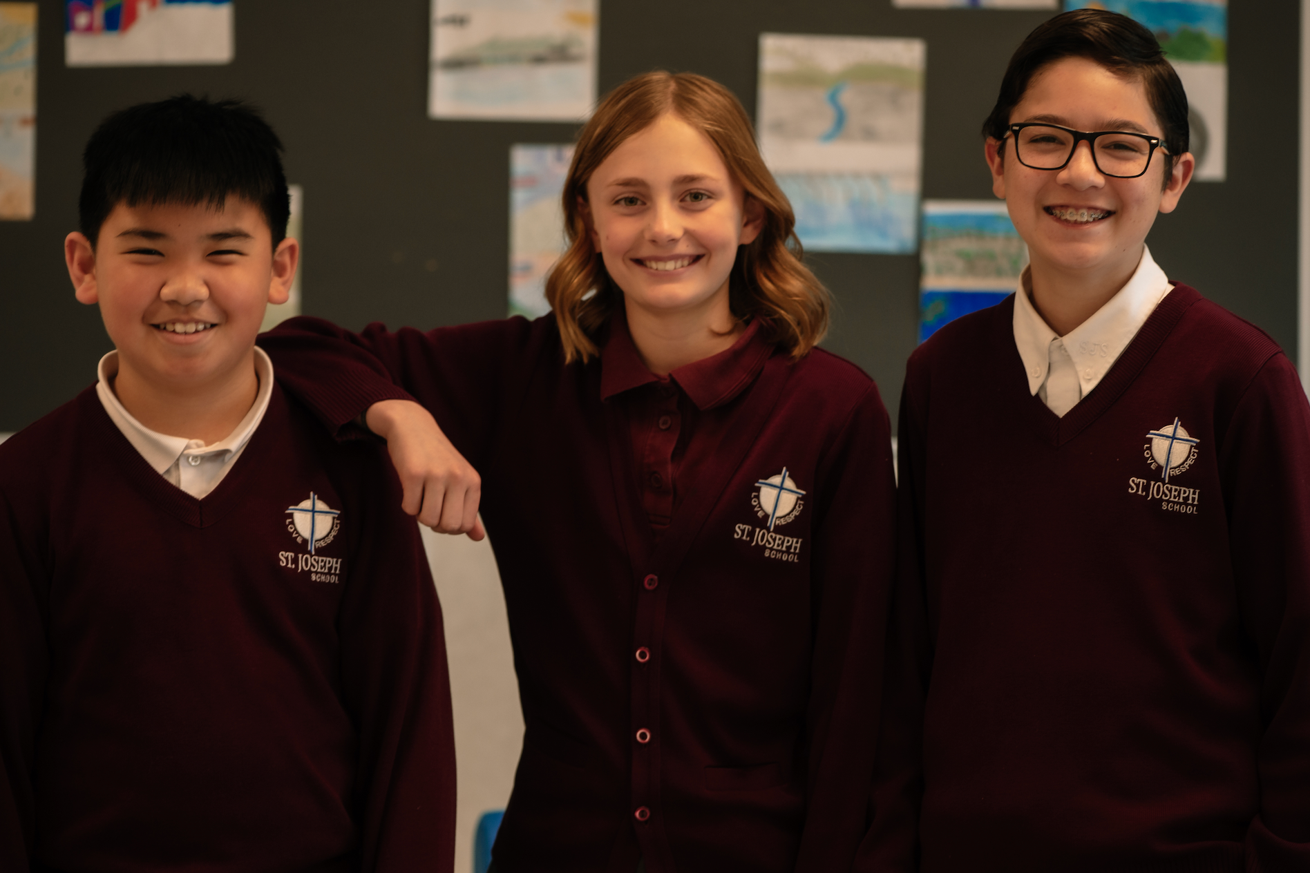 three students smiling for the camera with their arms around each other