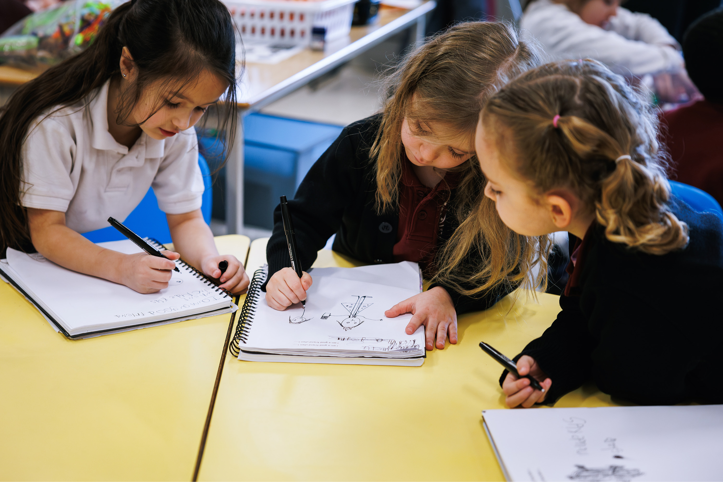 young girls drawing at a table