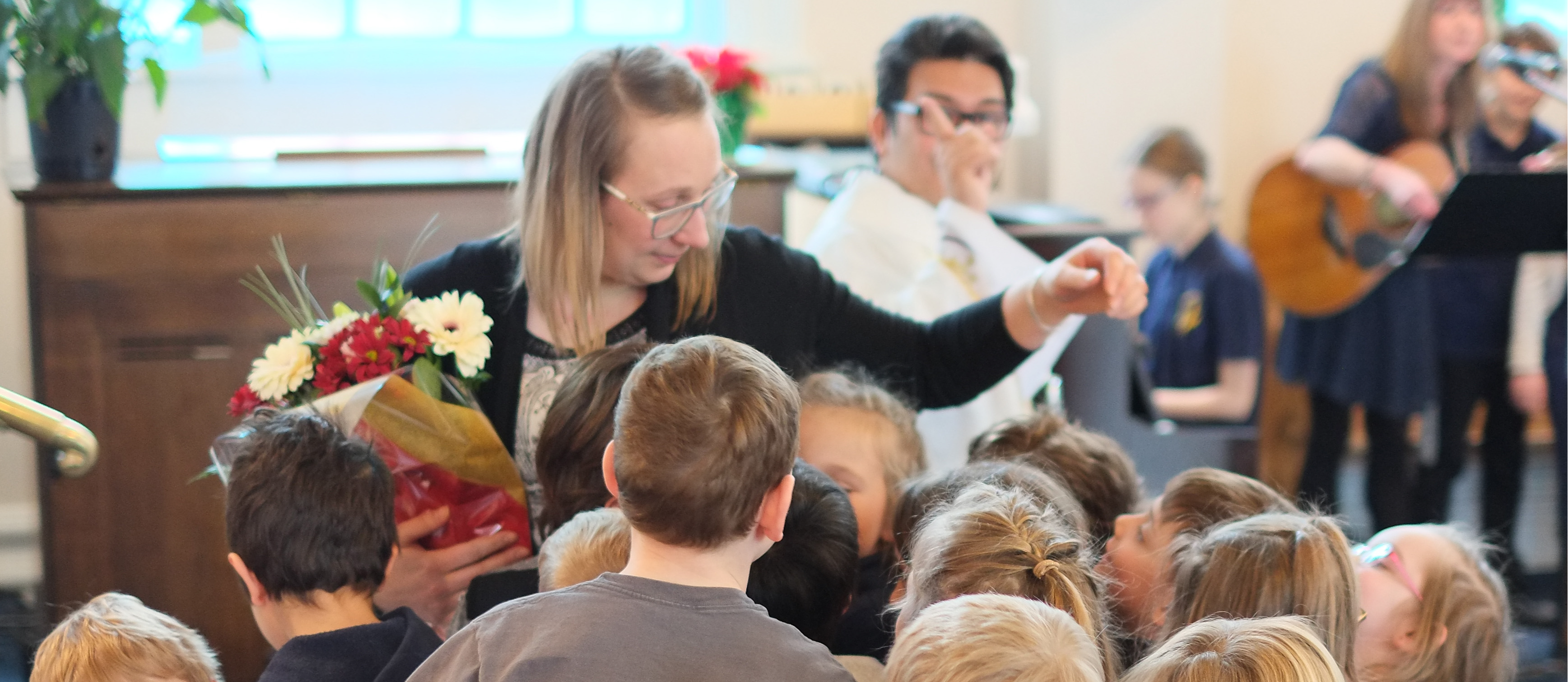 teacher with flowers hugging students