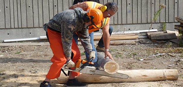 A group of men working on logs in a clearing.