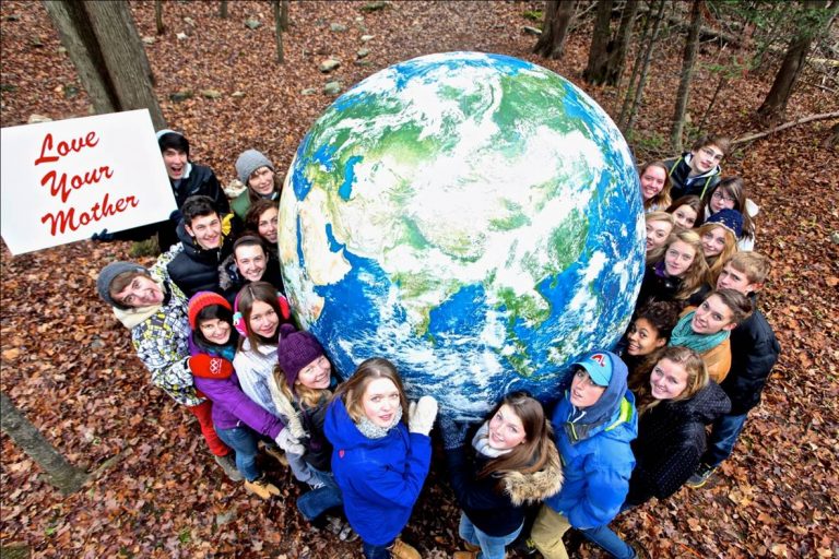 group of students out in the forest next to an earth globe