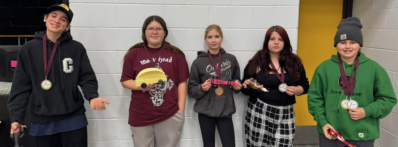 5 grade 8 students standing with their medals and their derby cars