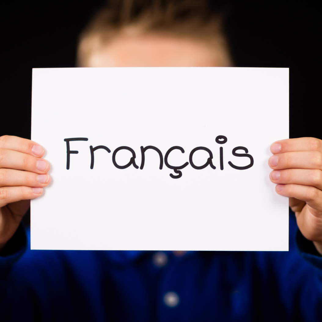Child holding a piece of Paper labelled Francais