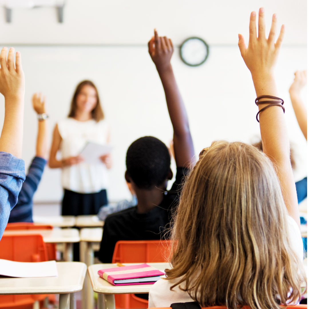 Students in a classroom with arms raised