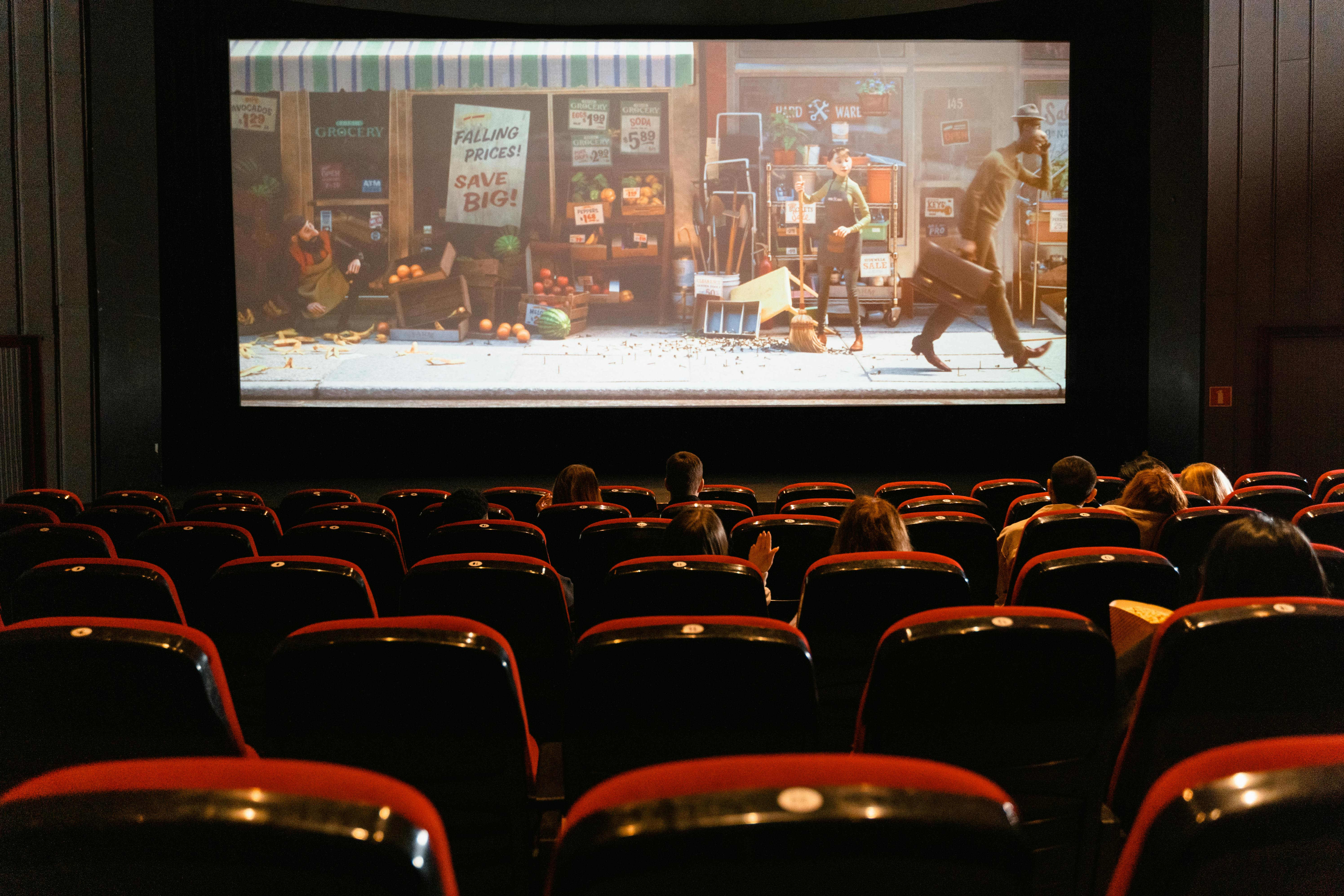 Rows of seats in front of  a large screen with a movie playing 