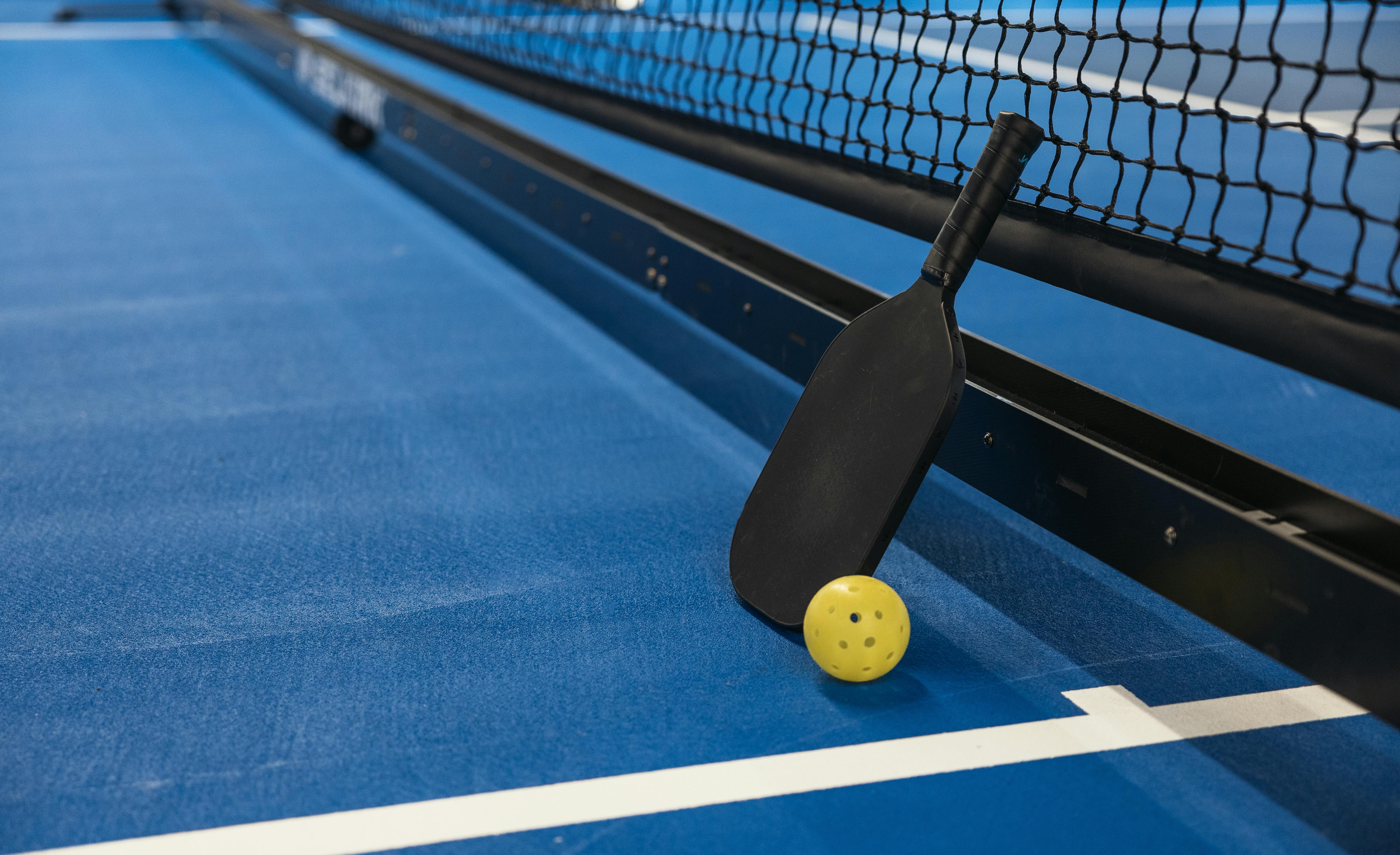 Pickleball paddle and ball on a blue court