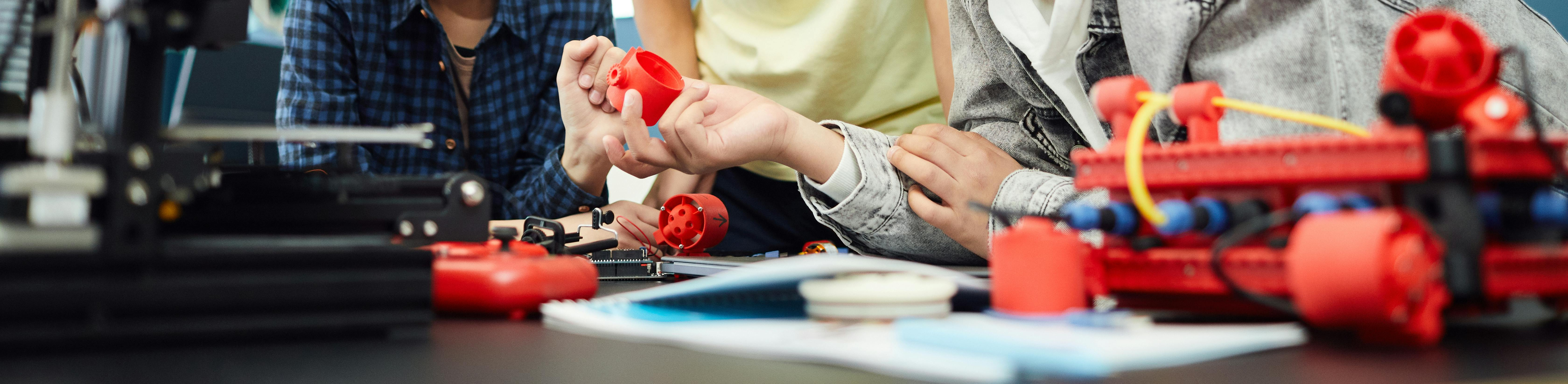 Three students examining 3D printed materials in front of a 3D printer