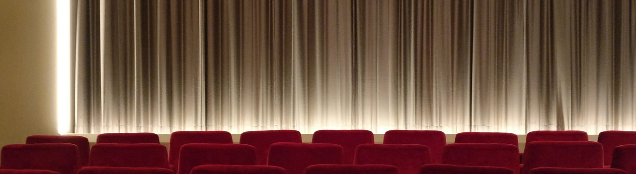 Rows of red fabric chairs in front of a large curtain
