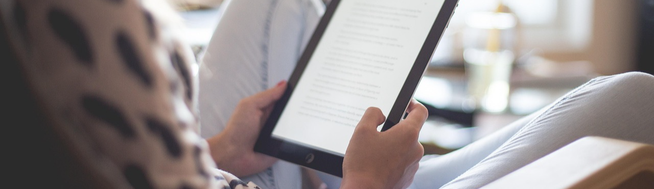Photo of a person reclining in a chair, reading an eBook on a tablet